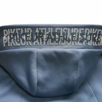 Kaptur ozdobiony szerokim mankietem z silikonowymi wypukłymi napisami PIKEUR Athleisure oraz podszyty śliskim, błyszczącym materiałem nadającym bluzie wyjątkowego charakteru.